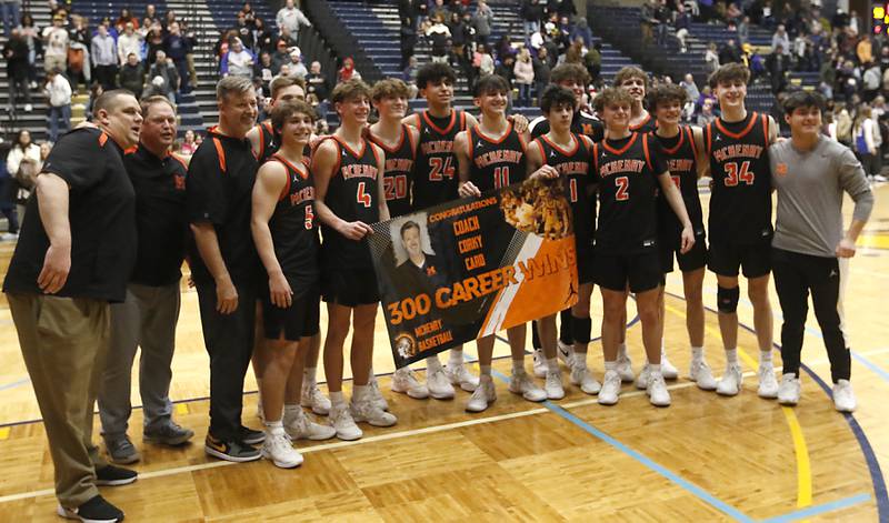 McHenry players pose for a photographs with their McHenry Head Coach Corky Card after he secured his 300 career win against Hononegah in the IHSA Class 4A Guilford Boys Basketball Sectional semifinal game on Wednesday, Feb. 28, 2024, at Rock Valley College in Rockford.