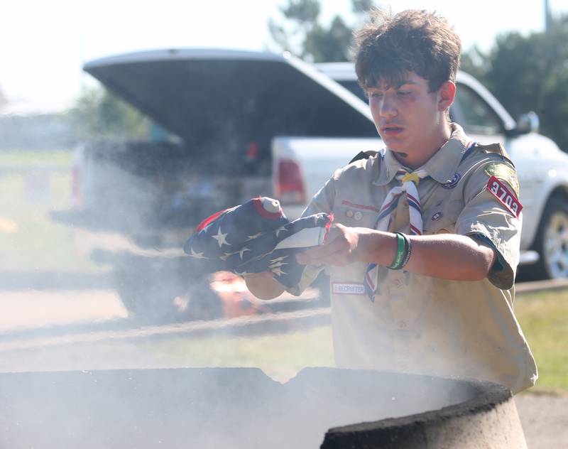Boyscout Dominic Morgan places an American Flag into a burning cauldron during a Flag Retirement Ceremony on Friday, June 14, 2024 at Veterans Park in Peru.  The ceremony always takes place on Flag Day. It began as a Eagle Scout project for area boy scouts about 30 years ago. Boy Scouts from Peru's Troop 123 and Peru Cub Scouts from Pack 3709 were on hand to help with the ceremony. When an American Flag gets torn and tattered, Flag etiquette requires it to be proper disposed in a burning cauldron.