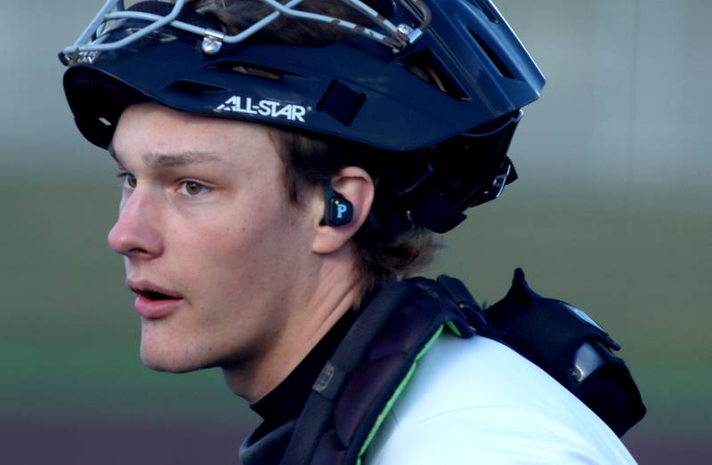 McHenry catcher Kamrin Borck received pitch calls via earpiece from McHenry’s pitching coach Zach Badgley against Huntley in varsity baseball at McHenry Friday night.