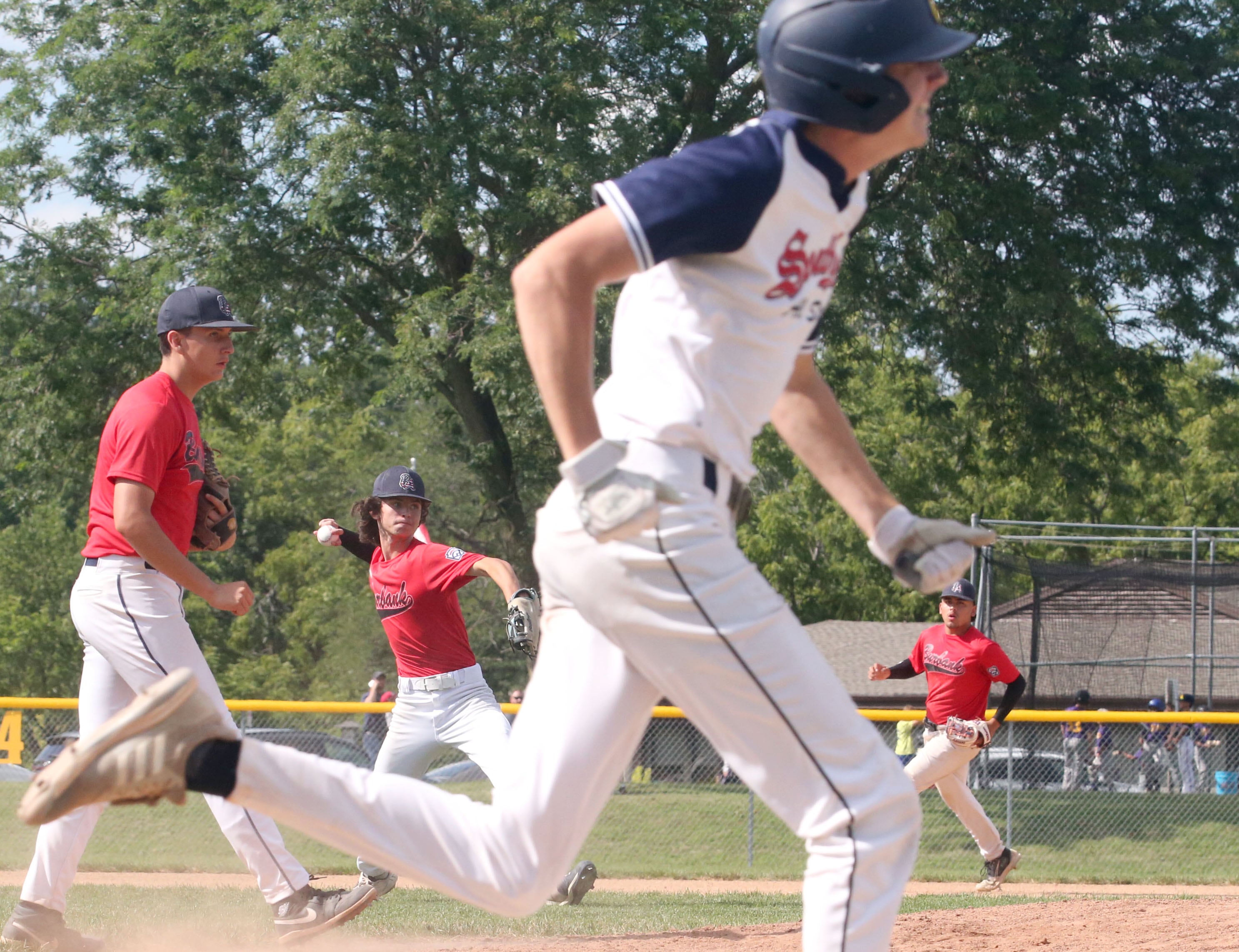 Burbank's Domo Divirgillo throws to first base to force out Michigan's Ryer Olsson during the Central Regional Baseball Tournament championship on Thursday, July 18, 2024 at J.A. Happ Field in Washington Park in Peru.