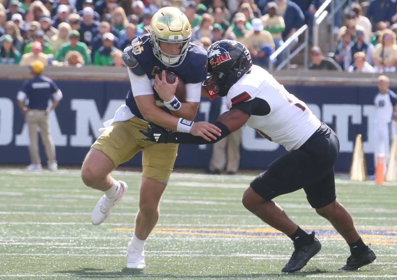 Notre Dame quarterback Riley Leonard runs with the ball as NIU's Jaden Dolphin makes the tackle on Saturday, Sept. 7, 2024 at Notre Dame Stadium.