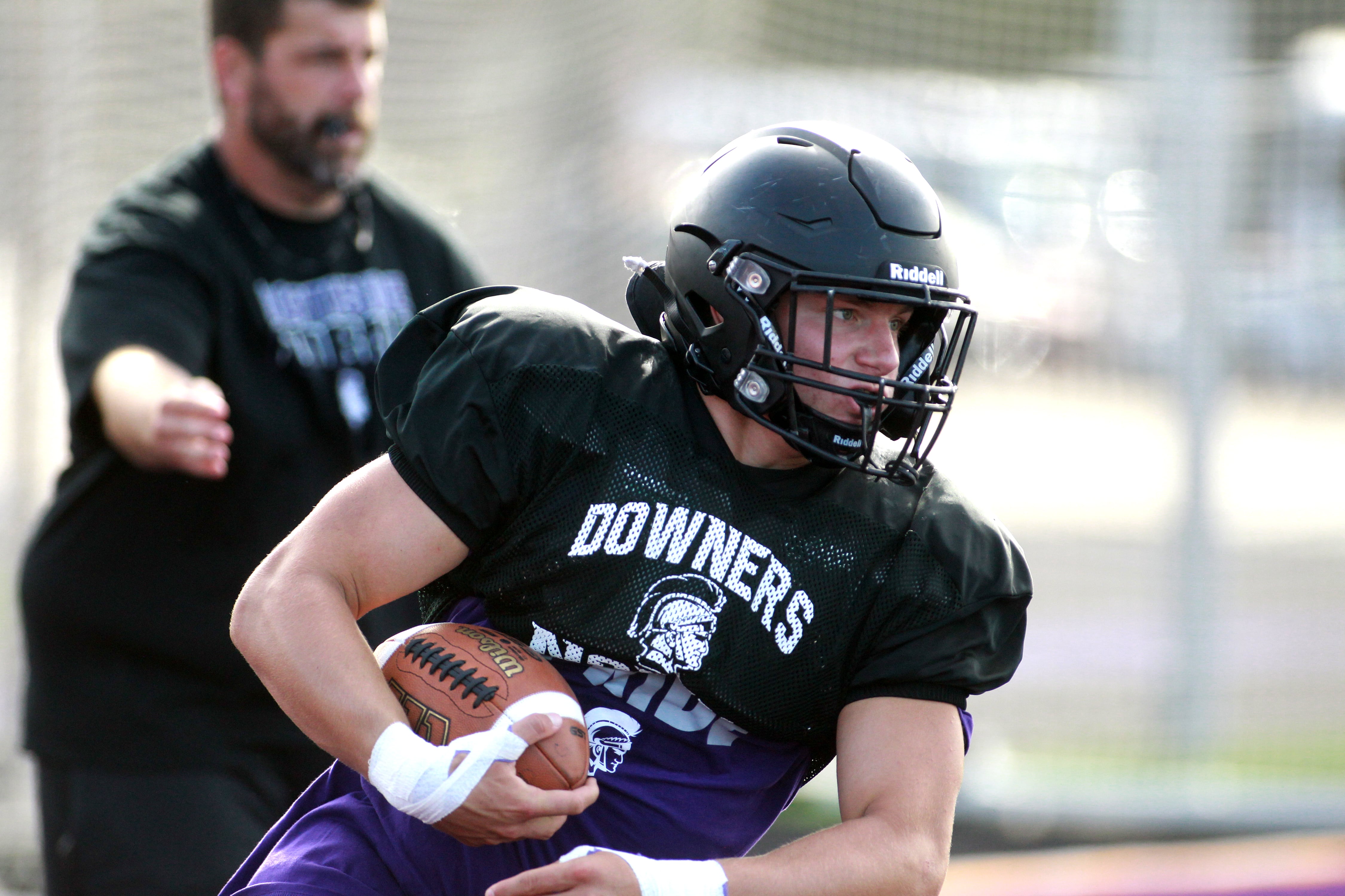 Downers Grove North’s Jake Gregorio is handed the ball during a practice on Tuesday, Aug. 20, 2024 at the school.