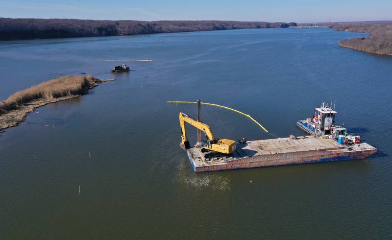 Workers use an amphibious dump truck (top) and a barge with excavators (bottom) to haul silt near Delbridge Island about a mile east of the Starved Rock Lock and Dam on Tuesday, Feb. 13, 2024 near Starved Rock State Park. The Starved Rock Breakwater project is a habitat restoration effort designed to restore submerged aquatic vegetation in the Illinois River, Starved Rock Pool. It will increase the amount and quality of resting and feeding habitat for migratory waterfowl and improve spawning and nursery habitat for native fish.
Construction of the breakwater will involve placement of riprap along northern edge of the former Delbridge Island, adjacent to the navigation channel between River Mile 233 and 234. The breakwater structure will be approximately 6,100 feet long and constructed to a design elevation 461.85 feet, providing adequate protection to allow for submerged aquatic vegetation growth.
The estimated total cost of this project is between $5 and $10 million.