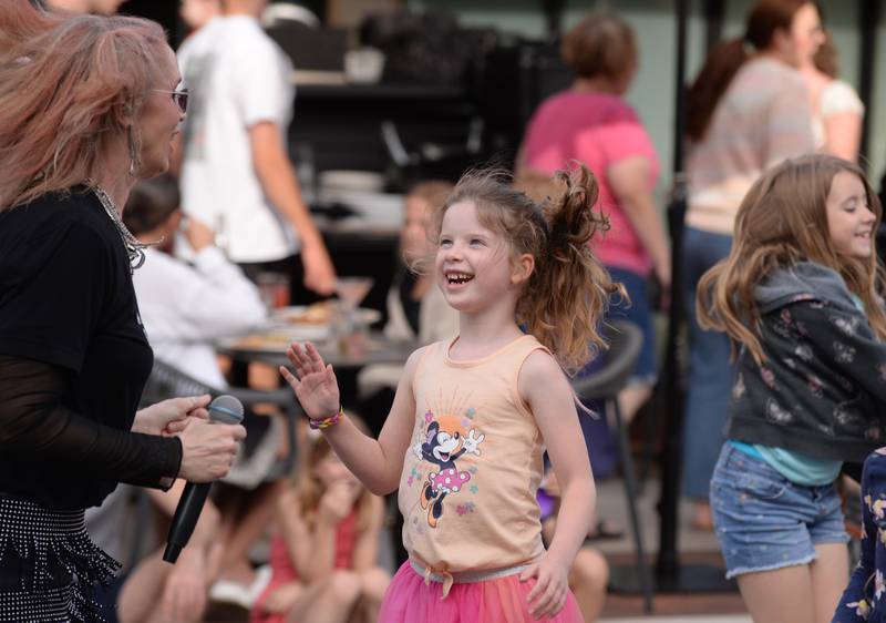 Altered Suburbia lead singer and teacher at Lincoln Elementary School, Amy Bishop entertains children including Edie Krastins of Downers Grove during the concert held downtown Glen Ellyn Friday June 8, 2024.