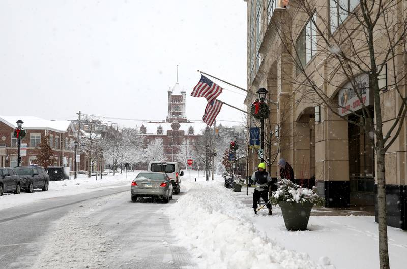 People shovel a sidewalk in downtown Wheaton following several more inches of snowfall in DuPage County on Friday, Jan. 12, 2024.