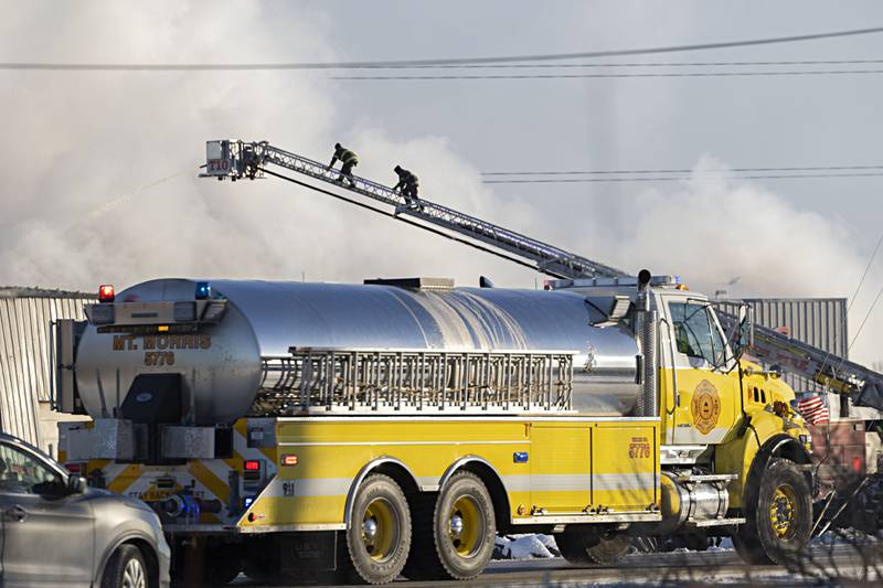Firefighters climb a ladder to pour water on a fire at Moore Tires in Rock Falls Tuesday, Jan. 16, 2024.