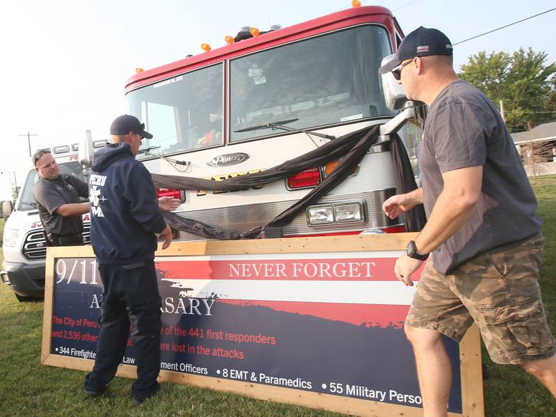 (From left) Peru Community Service officer Blake Frund, Peru EMS coordinator Brent Hanson and Peru Fire captain Bill Krolak place a 9/11 memorial at the Roundabout honoring on Wednesday, Sept. 11, 2024 at the roundabout in Peru.