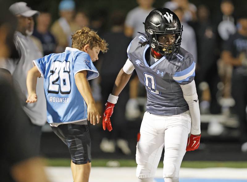 Willowbrook's Kenneth Rhodes (0) is congratulated by ball boy Michael Rovansek after a touchdown during the varsity football game between Glenbard East and Willowbrook high schools on Friday, Sep. 30, 2024 in Villa Park.