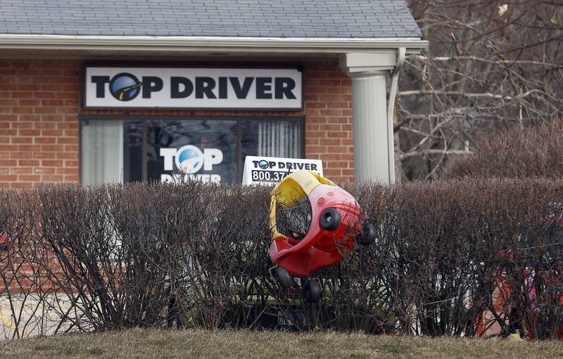 A lone children’s car sits wedged in the bushes next to a driving school vehicle Wednesday, Feb. 28, 2024 in Geneva. Severe storms hit the area late Tuesday evening causing wind and storm damage to the Pepper Valley neighborhood and surrounding areas.