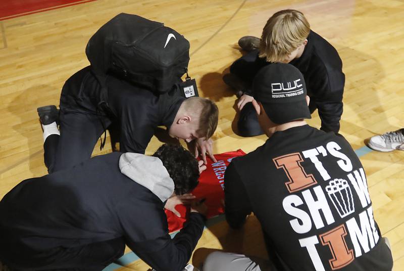 Jimmy Mastny and other wrestlers sign a wrestling singlet after Marian Central honored their wrestlers that brought home the IHSA Class 1A Dual Team State Championship title on Friday, March 8, 2024, during a celebration at the high school in Woodstock.