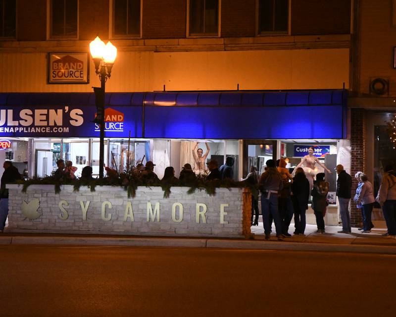 Community members watch dancers from the Northern Illinois Dance Center perform in the window of Paulsen's Appliance Store in downtown Sycamore on Friday Nov. 17, 2023, during the Sycamore Chamber of Commerce's annual Moonlight Magic.