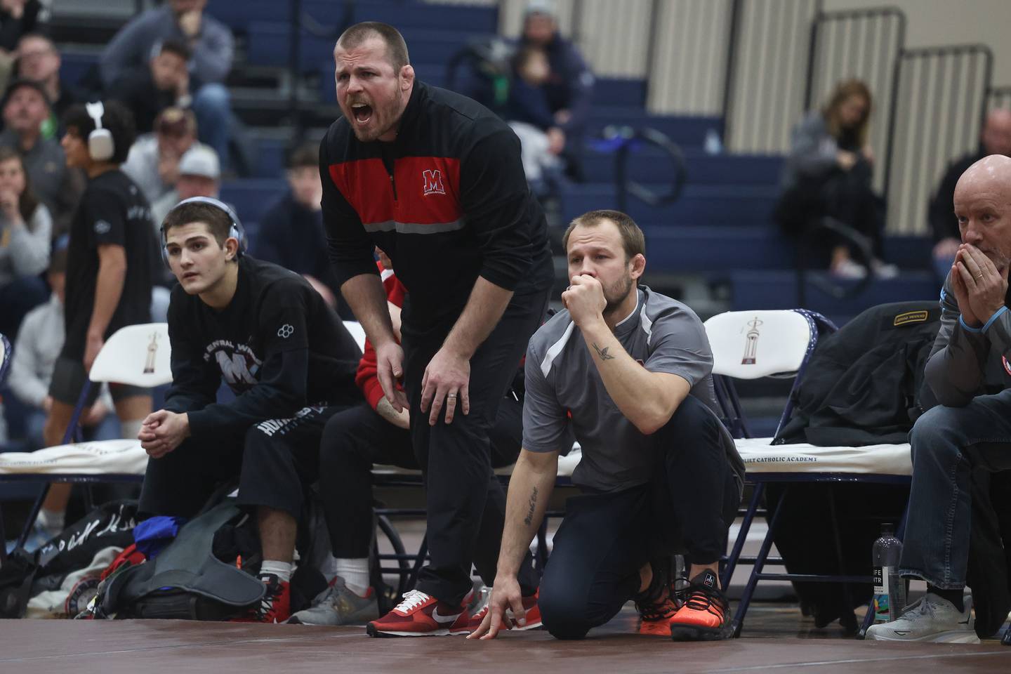 Marian Central co-coaches Jordan Blanton yells out to a wrestler while Ryan Prater kneels for a lower view during a match against Joliet Catholic in the tri-meet at Joliet Catholic on Thursday, Jan. 18th, 2024 in Joliet.