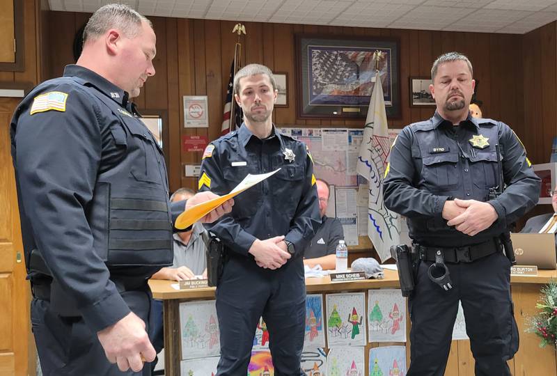 Marseilles Police Capt. Todd Gordon (left) reads the credit of officers James Buckingham (middle) and Mike Byrd as part of their promotion to the rank of  sergeant, part of the Marseilles City Council meeting on Wednesday.