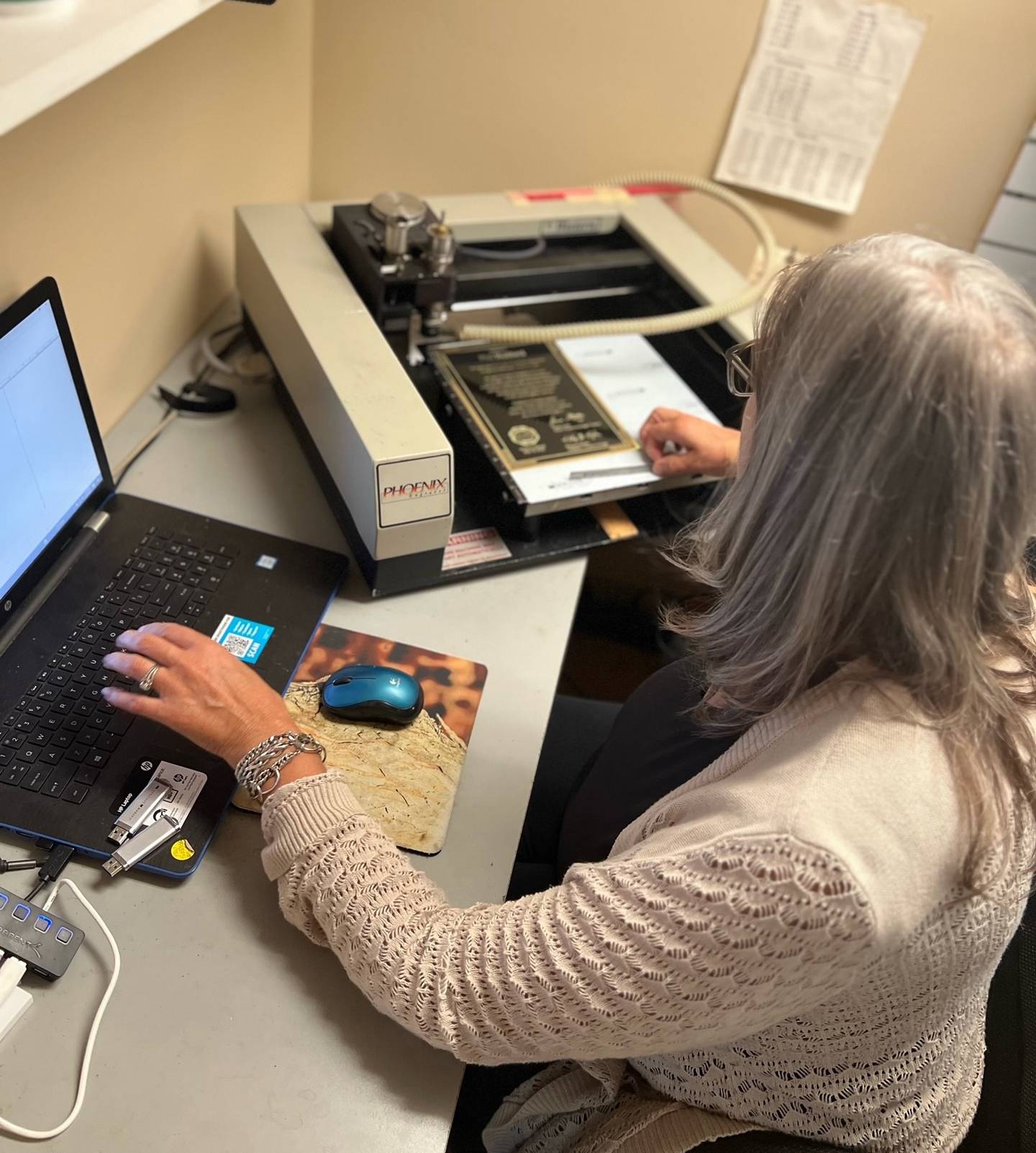 Patty Donahue, owner of Image Awards Engraving and Creative Keepsakes Inc. in Geneva, works on Visions Phoenix 1212 equipment for an engraving project.