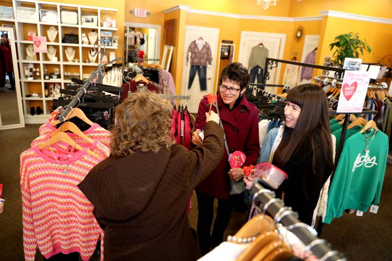 Random Acts Matter volunteer Tina Lappa hands out orange roses to Juli Brainard (top left) and Annette Dupre at Jeans and a Cute Top Shop in St. Charles as part of Random Acts of Kindness Week on Wednesday, Feb. 14, 2024.