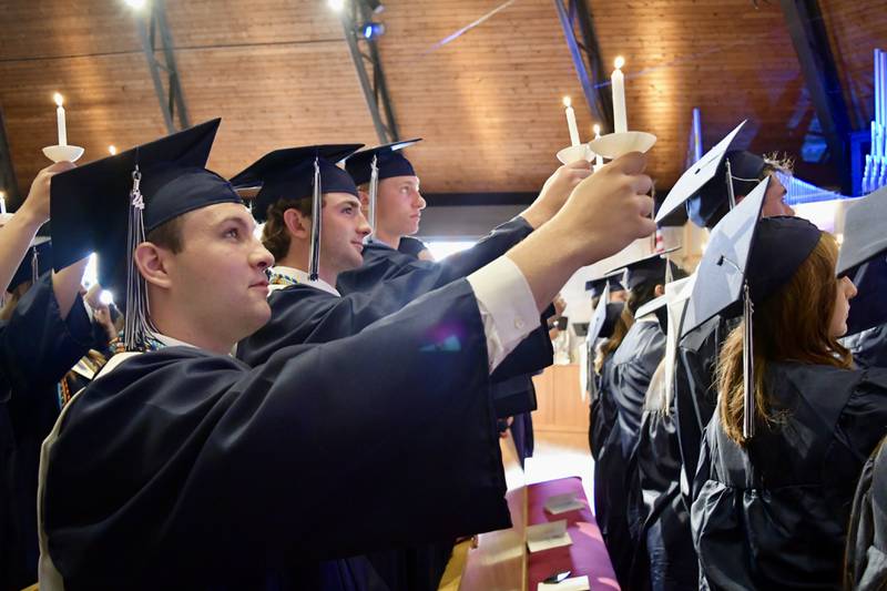 Nazareth Academy graduates Dan D"Andrea, Kevin Dalton and Ryan de Jonge raise the alumni flame during the school’s commencement ceremony at Christ Church in Oak Brook on Sunday, May 19, 2024.