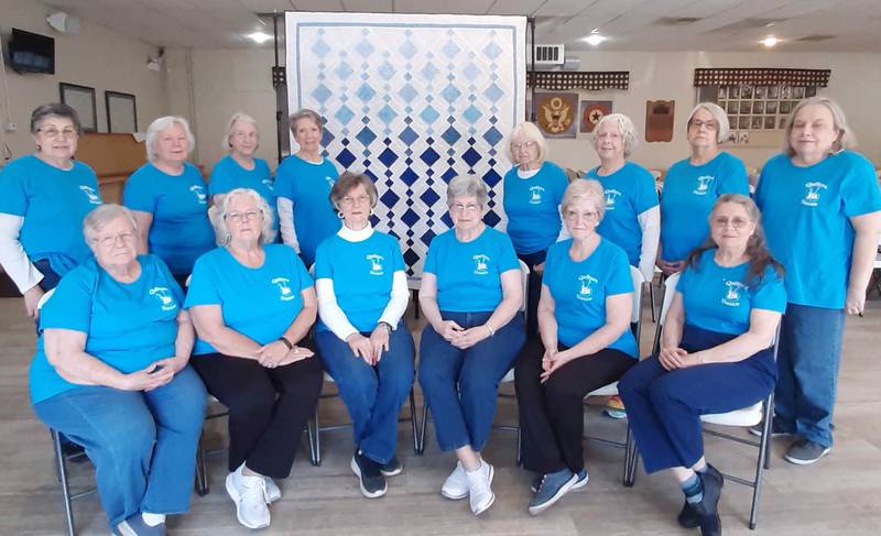 Members of the Quilters Dozen Quilting Club of Oswego pose with “Blue Chandelier,” the 2024 PrairieFest Quilt to be raffled off during this year’s Oswegoland PrairieFest community celebration.