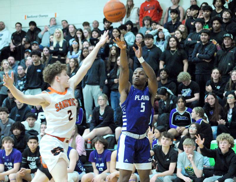 Plano's Waleed Johnson (5) shoots a three-point shot over Sandwich defender Griffin Somlock (2) during a varsity basketball game at Sandwich High School on Tuesday, Feb. 13, 2024.