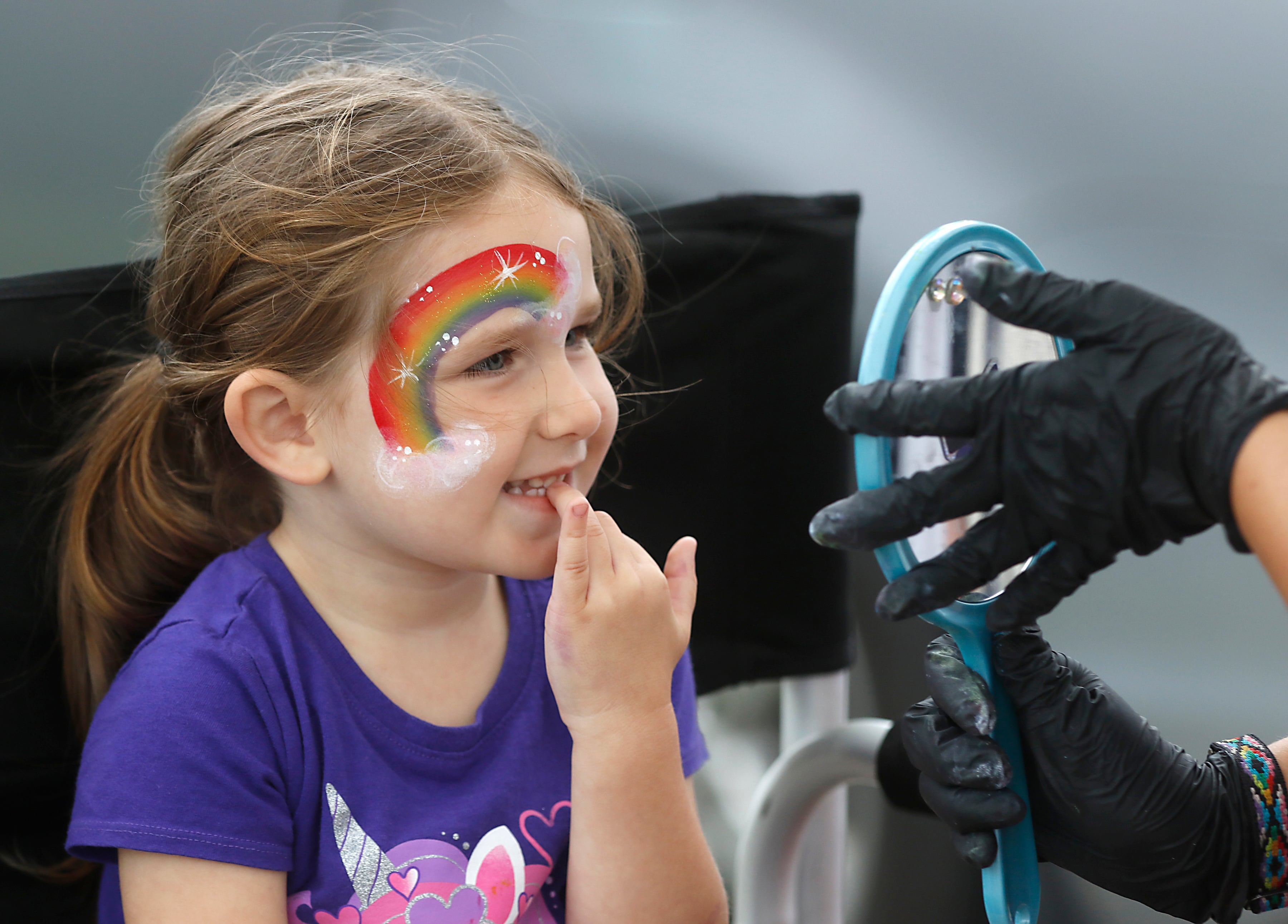 Addison Lundy, 3, looks a her face having a rainbow painted during a National Night Out event Tuesday, Aug. 6, 2024, at Petersen Park in McHenry. This year's event featured officers from theMcHenry County Sheriff's Department, McHenry County Conservation District Police, and the McHenry Police Department. and the police departments of McHenry along with games, face-painting, K-9 and motorcycle demonstrations, food and family fun.