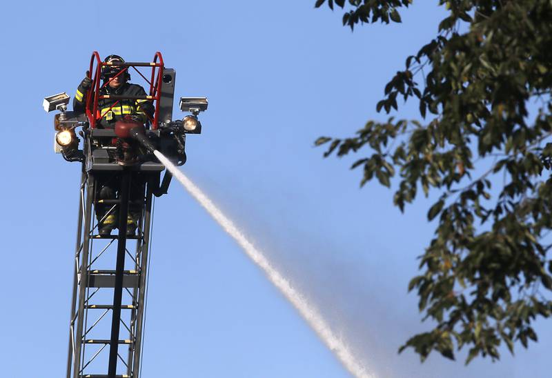 A firefighter battle a house fire in the 300 block of Lincoln Avenue in Woodstock Monday, Oct. 9, 2023, after an explosion following suspected gas leak in the area.