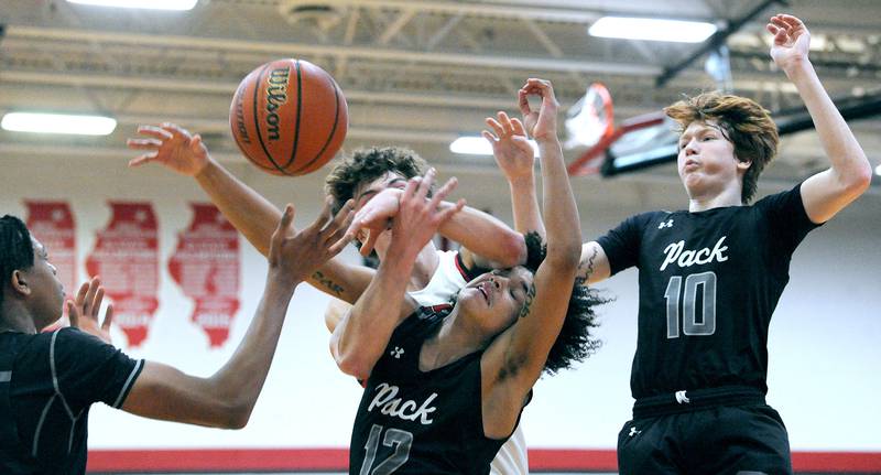 Oswego East's Drey Wisdom (12) and Yorkville's Bryce Salek get tangled up fighting for a rebound during a varsity basketball game at Yorkville High School on Friday, Feb. 9, 2024.