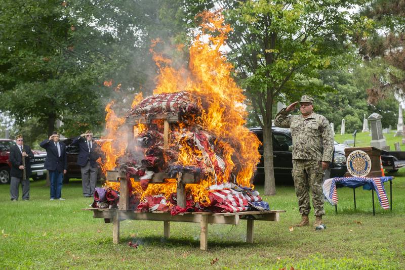 Morrison American legion senior vice commander Dennis VanZuiden, salutes after alighting nearly 600 flags during a retirement ceremony Sunday, Sept. 25, 2022. Worn and faded flags can be donated to the legion to be retired respectfully.