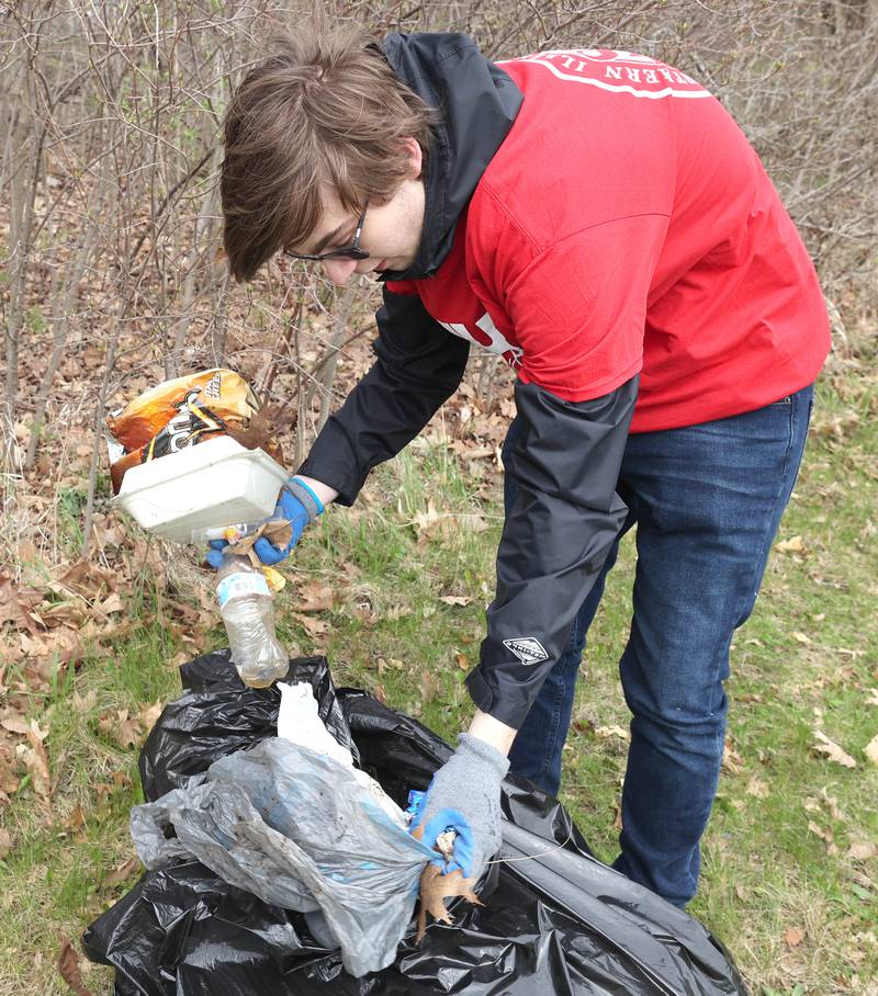 Northern Illinois University sophomore Joseph Richards, from Crete, a member of NIU Cares, bags up garbage he collected Friday, April 29, 2022, on campus near the West Lagoon. NIU Cares, with the help of the Trash Squirrels, was hosting a community cleanup event, going to several locations in DeKalb to pick up litter.