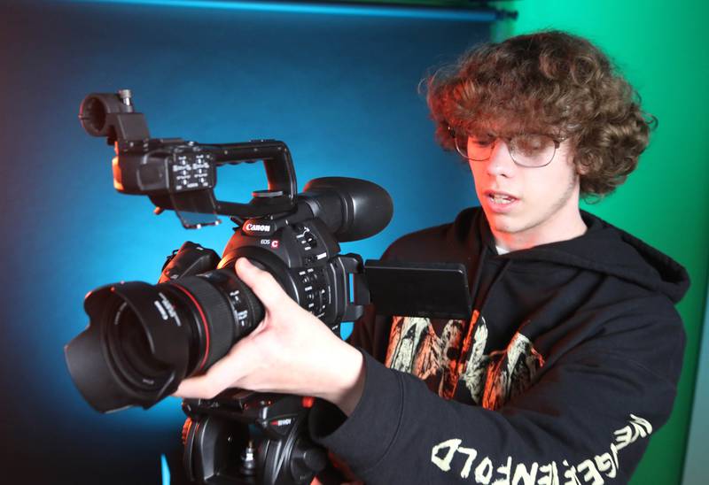 Johnny Howard, a junior at DeKalb High School, checks out a camera in the studio Thursday, March 7, 2024, at the school. Howard is part of the BarbCast network that broadcasts live streaming video of sports and events at the school as well as putting together promotional materials.