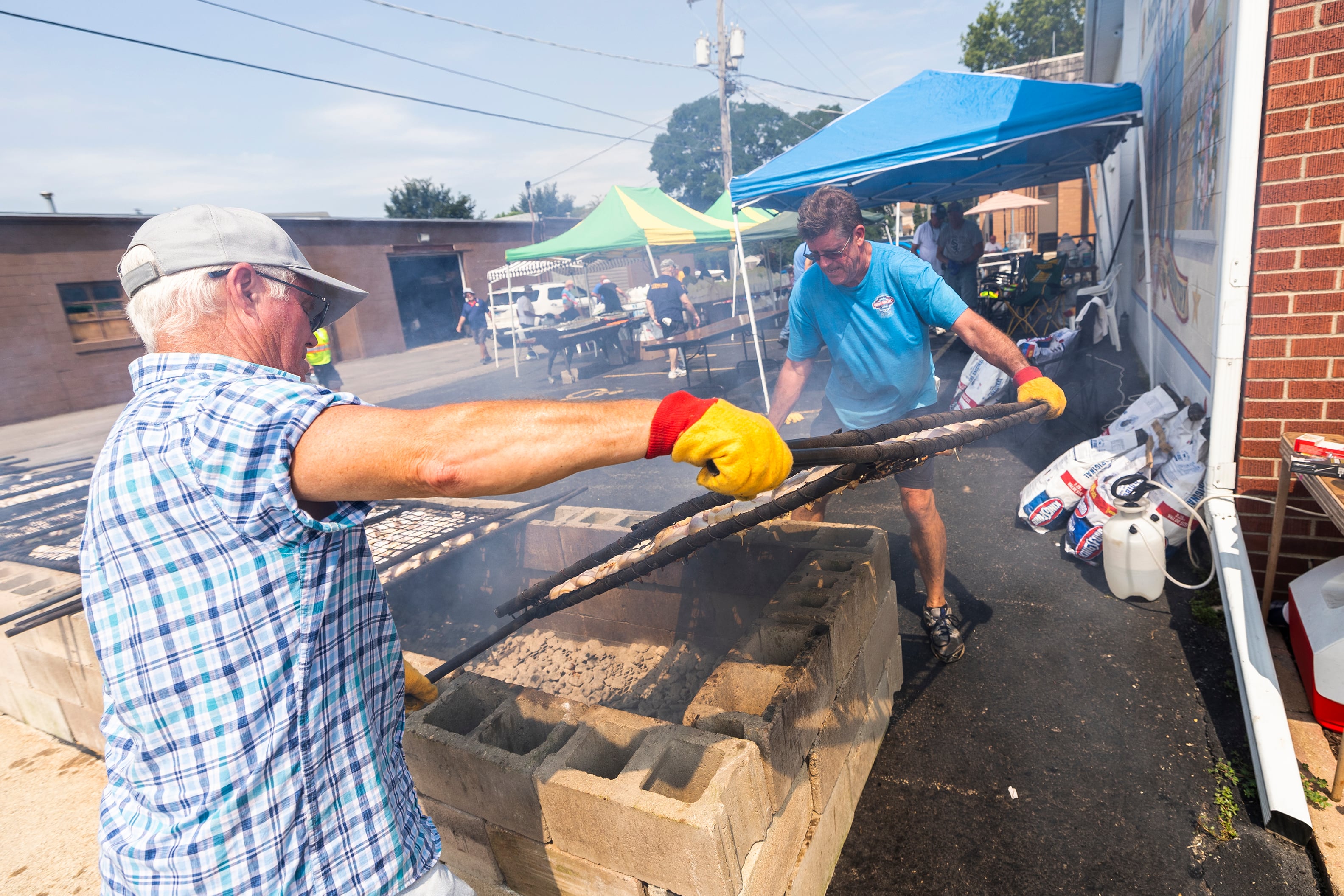 Mike Wheeler (left) and Terry Hammett flip one of 10 racks of chicken Monday, Aug. 5, 2024, at the Legion.