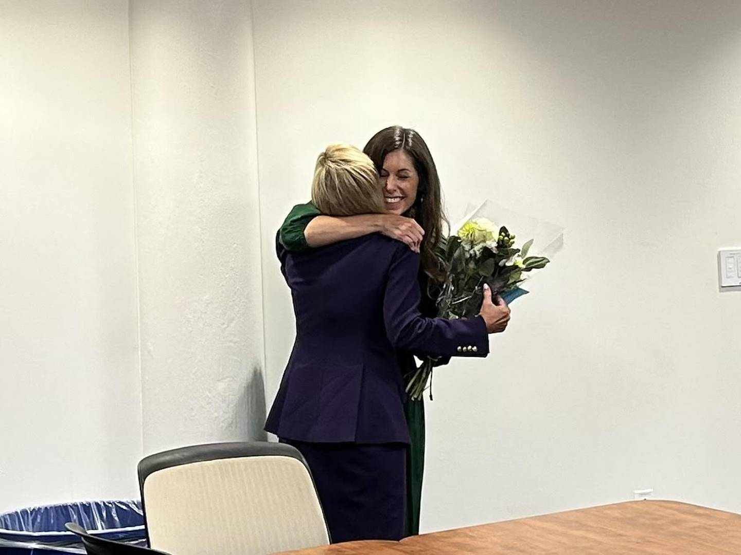 Kelly Rohder-Tonelli, Joliet Junior College's executive director of strategic engagement (in green), learned after a leadership meeting she would receive the 2024 ATHENA Award. Rohder-Tonelli is seen hugging Jen Howard, president of the Joliet Region Chamber of Commerce & Industry, which presents the ATHENA award each year.