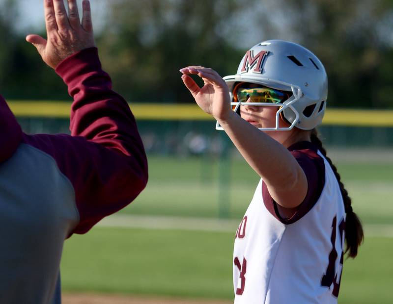 Marengo’s AJ Pillow is greeted at first base after a single against Richmond-Burton in varsity softball at Marengo Monday.