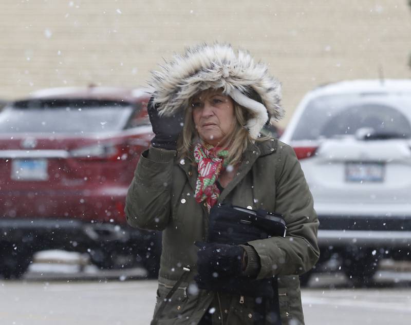 Tammie Kohl, of Woodstock, holds onto her hood as she crosses Brink and North Williams streets in downtown Crystal Lake as the snow begins to fall Thursday, Dec. 22, 2022.