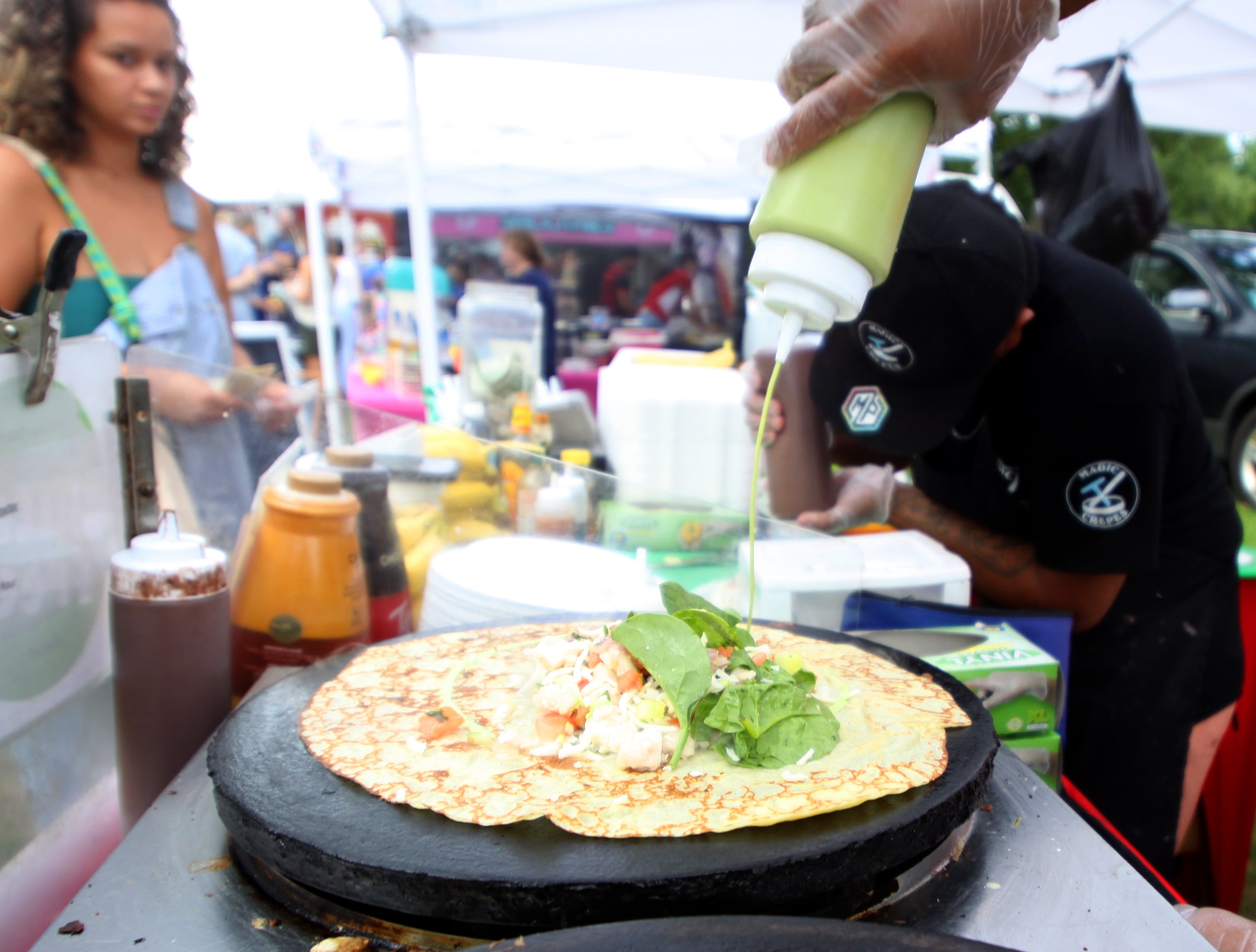 A customer waits for her crepe to be completed at the Magic Crepes booth as part of The Dole Farmers Market in Crystal Lake Sunday.