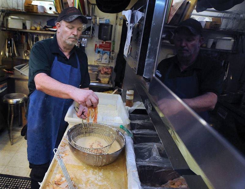 Cajun Connection owner Ron McFarlain prepares fried alligator, a popular menu item at the Utica restaurant.