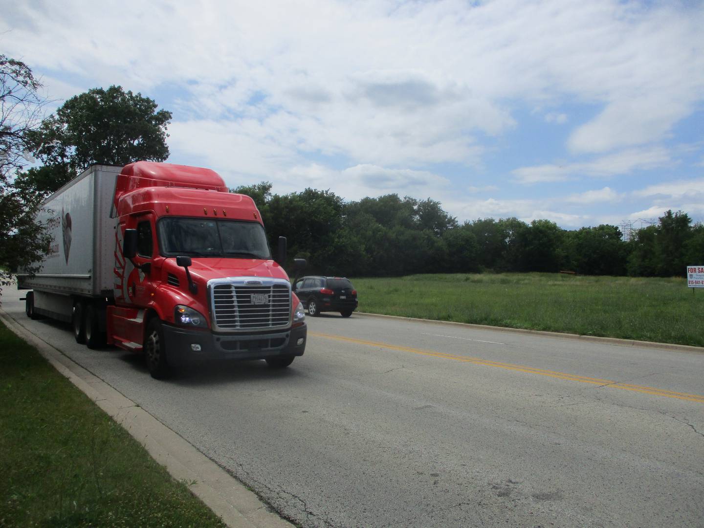 A semitrailer on Division Street, already a heavily used truck route, passes a site where a developer wants to build additional warehouses in Joliet.