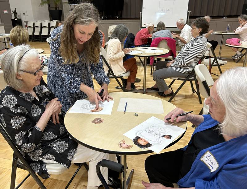 Gloria Fallon (left) and Randi Best (right) get some tips from Bethe Hughes (center) on their sketches during a forensic art program at the Coliseum Museum of Art, Antiques, and Americana in Oregon on Saturday, Aug. 17, 2024. Hughes, a special agent and forensic artist, worked  for the Illinois State Police and was the presenter for the program.