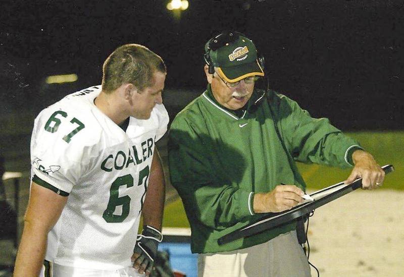 Ken Miller, who was inducted April 2 into the Illinois High School Football Coaches Association Hall of Fame, goes over blocking schemes with one of the offensive linemen he mentored at Coal City.