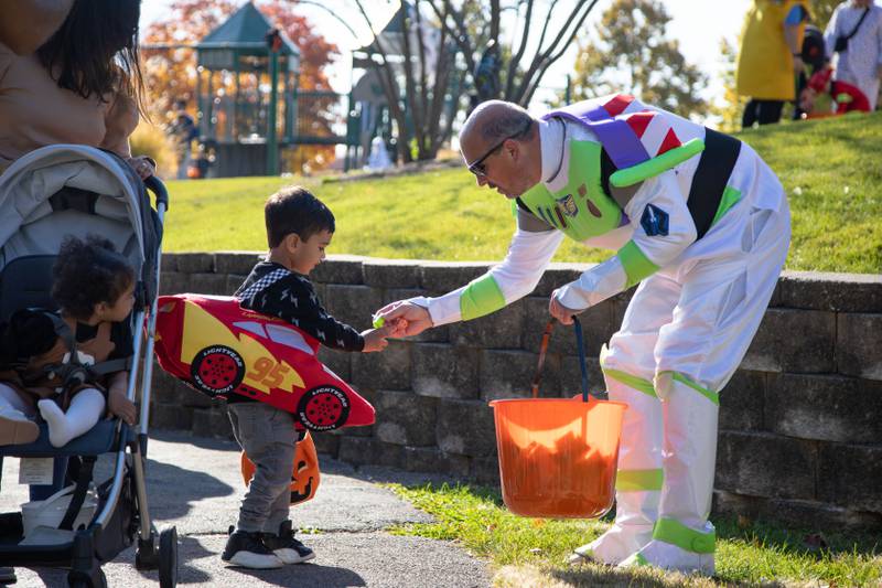 Mike Gustello of Lombard, right, hands Sunil Dave (3) of Glen Ellyn candy and toys during Boo Bash at the Glen Ellyn Park District on Saturday, Oct. 22, 2022.