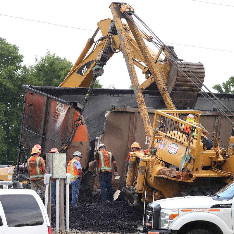 Workers check the damage after a tipped over coal car was uprighted following BNSF Railway train derailment Wednesday, July 10, 2024, near Route 34 on the west side of Somonauk.