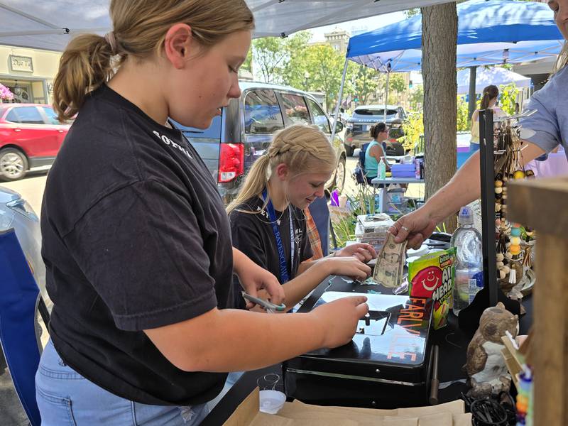 Sophia Sly (left) and Peyton Woods make a custom made bracelet at their business Owl Post on Saturday, Aug. 24, 2024, during the third annual Prairie Fox Books Children's Business Fair in downtown Ottawa.