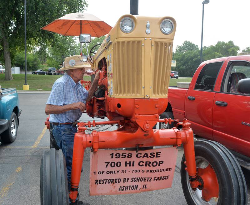 Remmer Schuetz, 88, of Ashton tinkers with the engine of his 1958 Case 700 H tractor awhile stopping at the Oregon Dairy Queen on Saturday during the Living History Antique Equipment Association's tractor drive. Schuetz has 70 Case tractors in his collection and this one is only one of six made in 1958 and 25 in 1959. It was made for sugar cane fields.