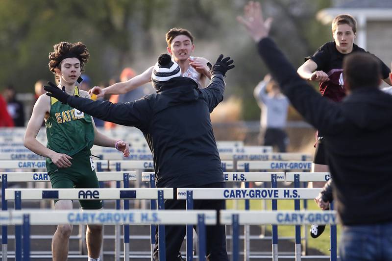 Coaches and race officials try to stop huddlers as the competition in the 110 Meyer high hurdles Friday, April 21, 2023, after a timing malfunction during the McHenry County Track and Field Meet at Cary-Grove High School.