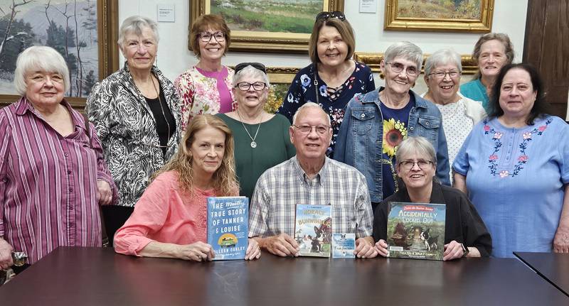 Members of the Oregon Woman’s Club present books to the Oregon Public Library in honor of long-time past president, Fran Strouse. Pictured, left to right, are:  Nancy Bartels, Christa Young, Jan Steward, Sharon Lung, Johanna Hahne, Sandi Chasm, Sandi Brubaker, librarian Deb Harmon, and Jan Larson. Seated are  Strouse daughters Cindy and Pam and Fran's husband, Clint.