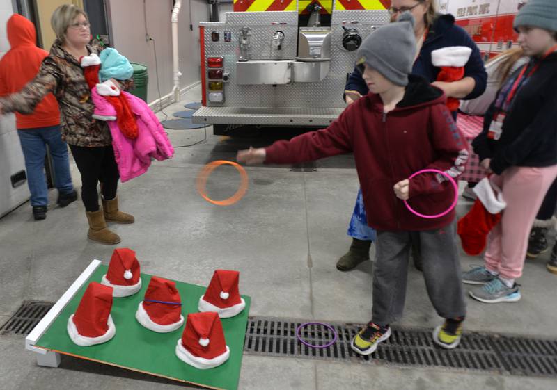 Lincoln Ford, 9 of Hillsdale tosses a ring onto a Santa hat as his mom Sarah, and sister Shiloh, 11. watch during kids events at the fire station during Erie's Hometown Holidays on Saturday, Dec. 2, 2023..