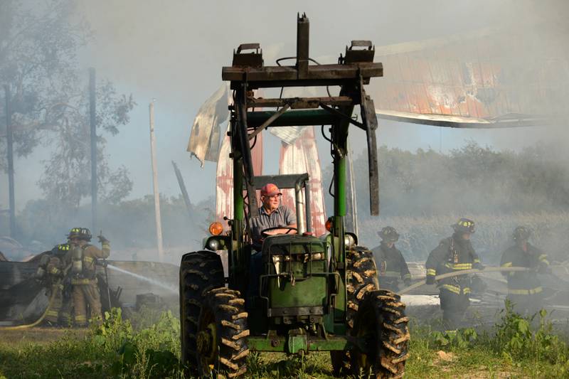 Lyle Hopkins of rural Polo uses a John Deere tractor to move large, burning round bales of hay away from a machine shed owned by his neighbor, Herschel Newcomer, during a Monday evening fire at 7015 W. Judson Road, southeast of Polo on Sept. 10, 2024. Several fire departments assisted the Polo Fire Department on the call. There were no injuries.