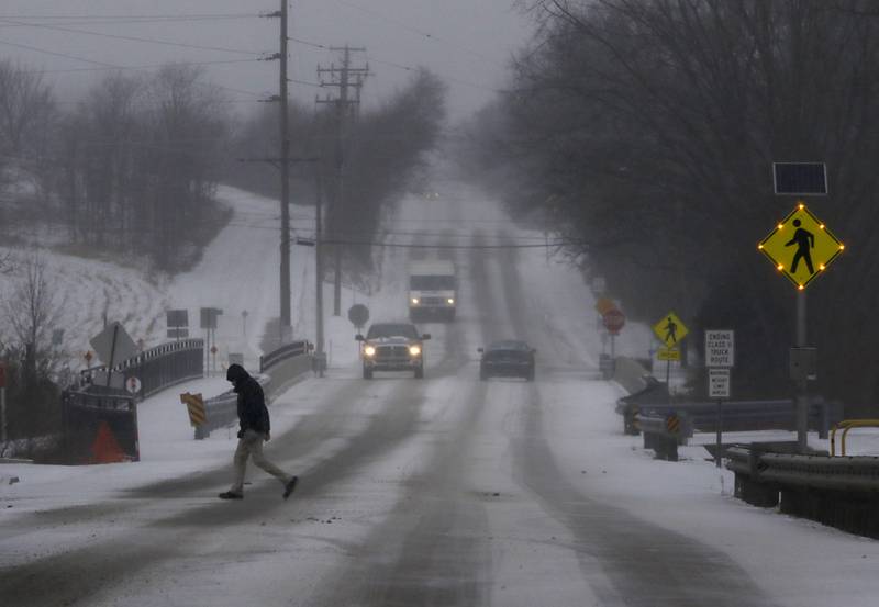 A worker crosses Winn Road to go to work at Scot Forge in Spring Grove on Thursday, Dec. 22, 2022, as a winter storm hits northern Illinois.