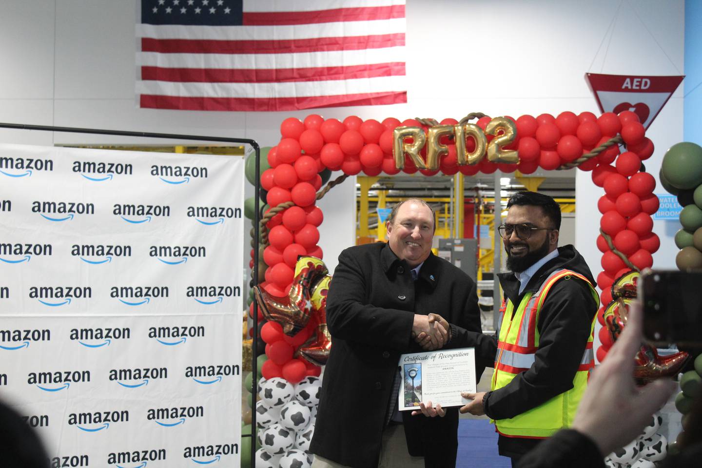 Huntley Village President Timothy Hoeft congratulates Amazon RFD2 General Manager Taseen Mohammed for the new Huntley Amazon warehouse opening.