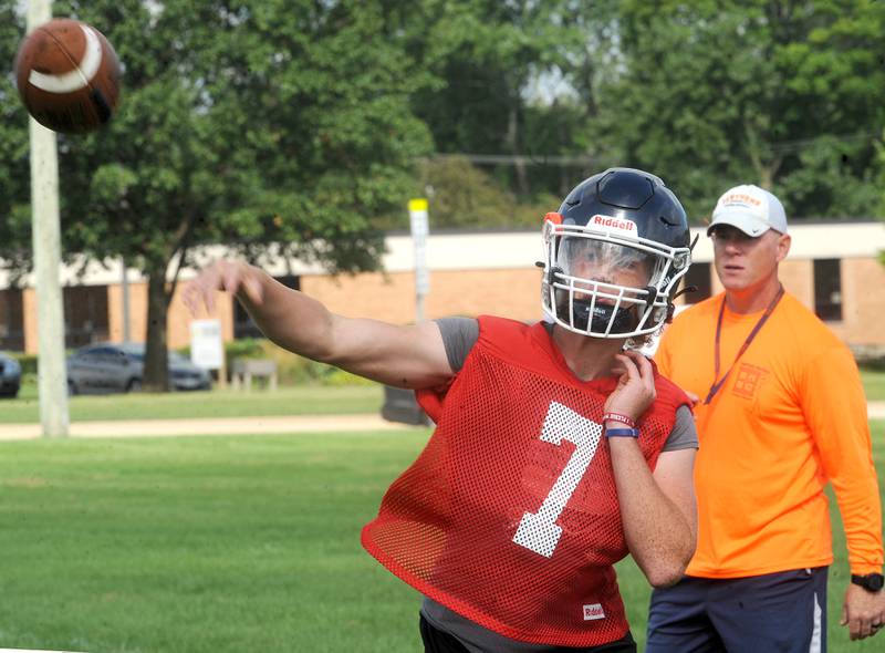 Oswego's Brett Connolly tosses a pass under the watchful eye of coach Brian Cooney during football practice at Oswego High School on Monday, Aug 7, 2023.