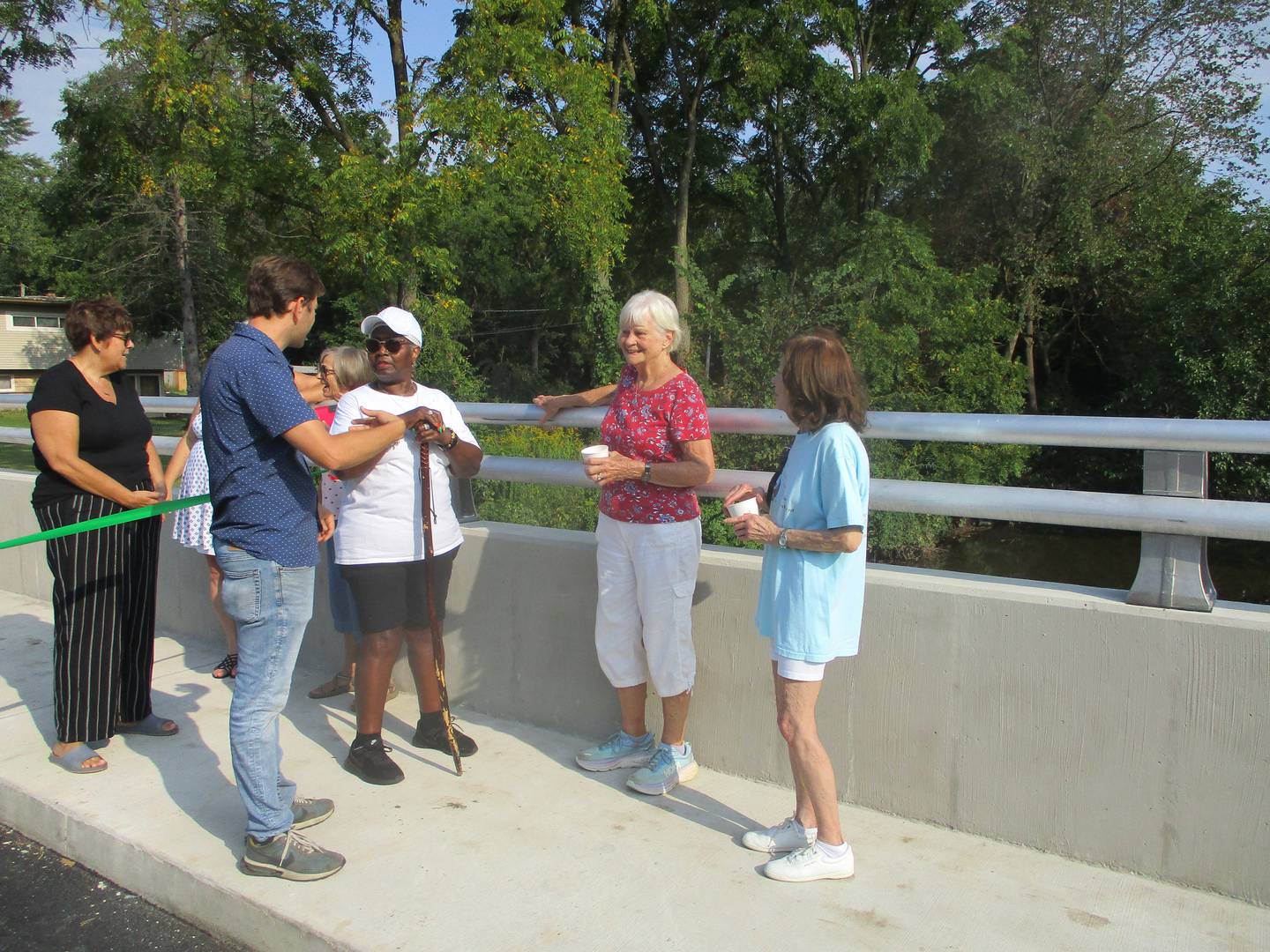 Sugar Creek resident Gerry Hamilton talks with Joliet Township Highway Commissioner Vincent Alessio about drainage problems in the neighborhood before a ribbon-cutting ceremony on Monday marking the opening of a new bridge carrying Sugar Creek Road over Sugar Creek. Aug. 26, 2024