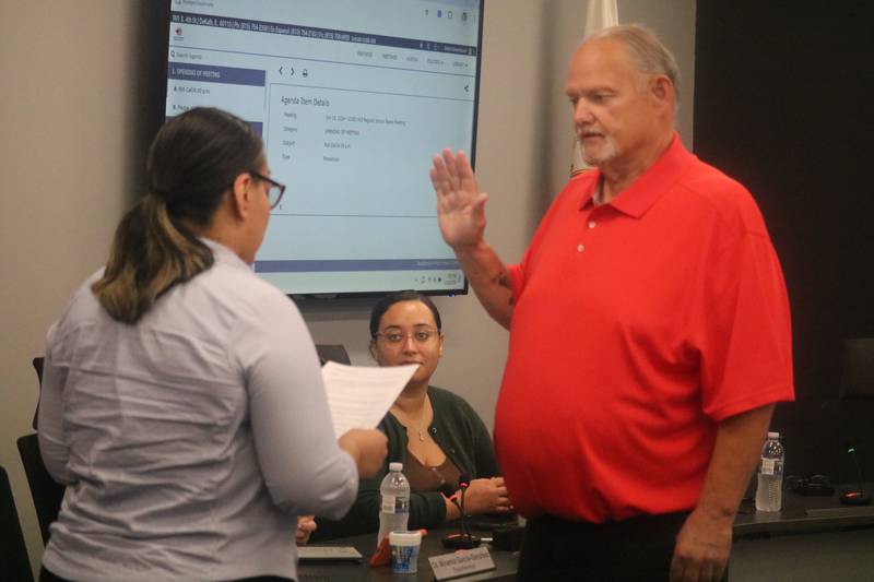 DeKalb resident Fred Davis (right) takes the oath of office June 18, 2024 at the DeKalb School District 428 Board meeting.